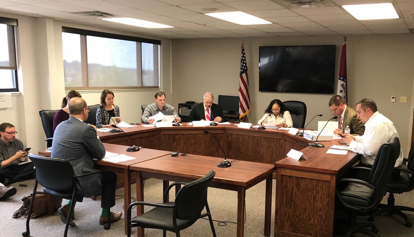 A meeting of the Arkansas MMC. Several people sit around wooden tables in an office room having a discussion.