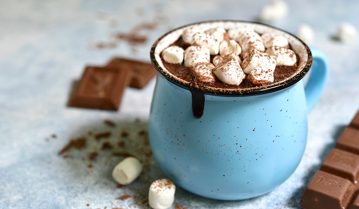 Hot chocolate in a blue ceramic mug topped with marshmellows.